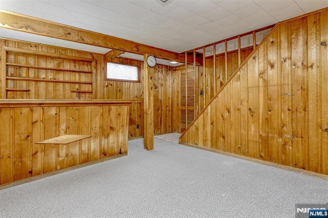 basement with wood walls, carpet, and stairs