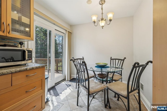 dining area with a chandelier, baseboards, and light tile patterned floors