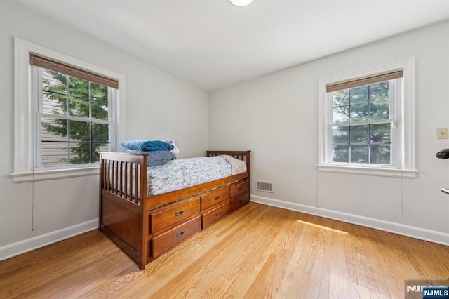 bedroom featuring light wood-style flooring, visible vents, and baseboards