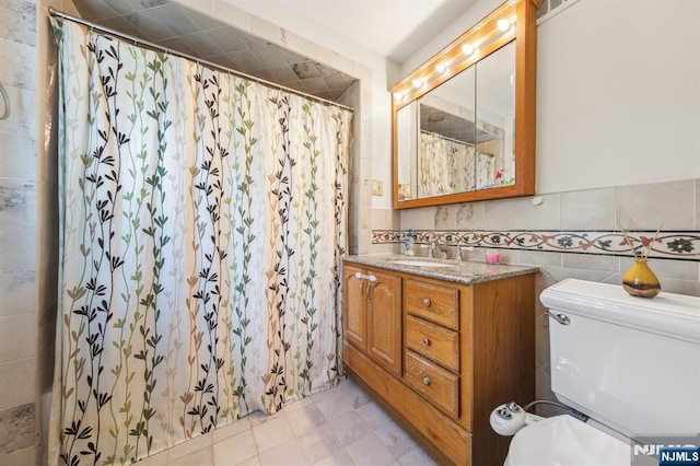 bathroom with tile walls, toilet, vanity, and a shower with curtain