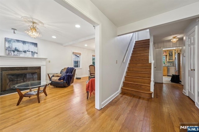 staircase featuring recessed lighting, a glass covered fireplace, wood finished floors, and baseboards