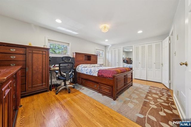 bedroom featuring light wood finished floors, recessed lighting, and two closets