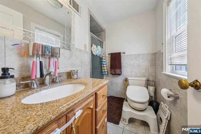 full bathroom with tile walls, visible vents, toilet, and tile patterned floors