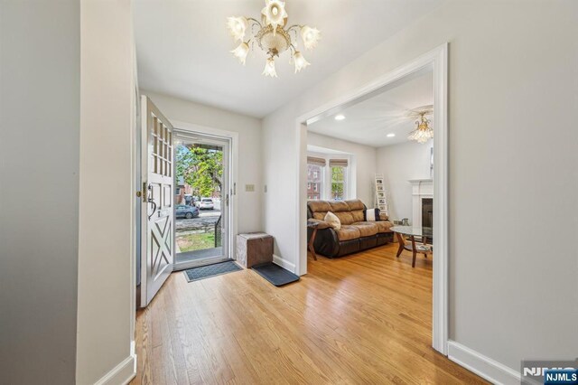 entrance foyer featuring light wood-type flooring, baseboards, recessed lighting, a chandelier, and a fireplace