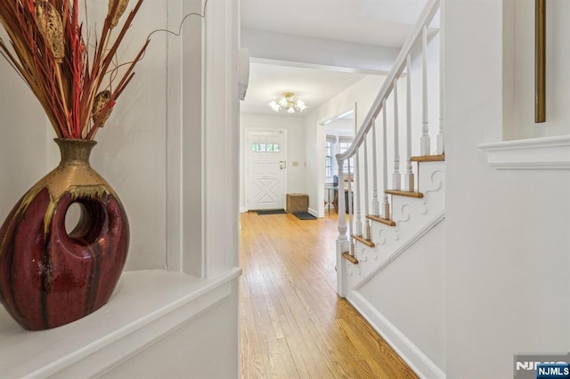 entrance foyer featuring light wood-style flooring, baseboards, and stairs