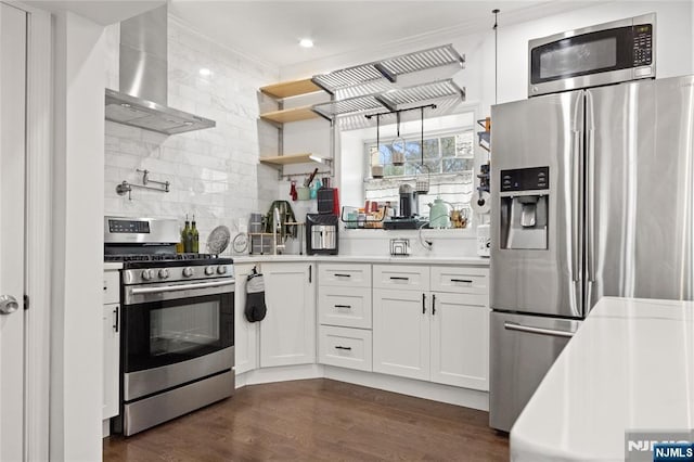 kitchen featuring wall chimney range hood, dark wood-style flooring, light countertops, stainless steel appliances, and tasteful backsplash