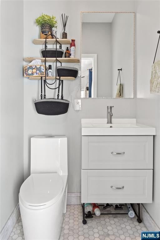bathroom featuring toilet, baseboards, and vanity