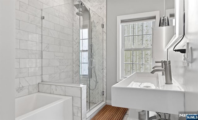 bathroom featuring a bath, a sink, a stall shower, and a wealth of natural light