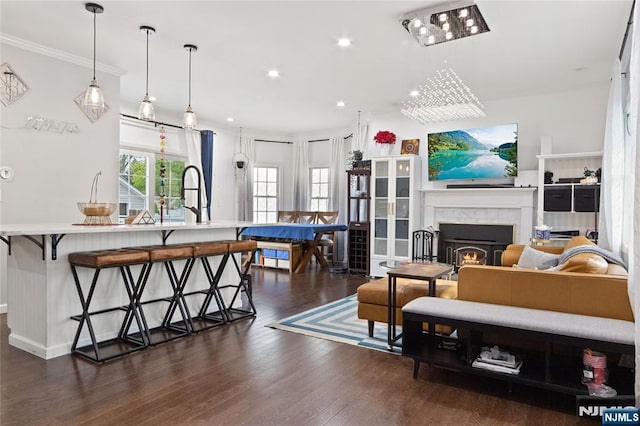 living area featuring recessed lighting, a lit fireplace, ornamental molding, and dark wood-type flooring