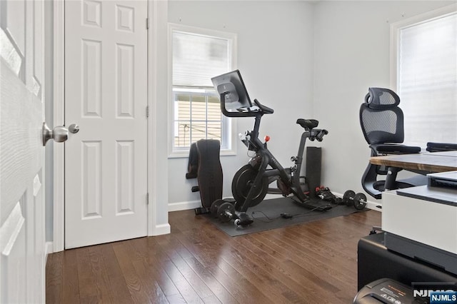 exercise area with dark wood-type flooring and baseboards