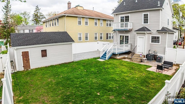 back of house featuring an outdoor structure, a fenced backyard, a gate, a balcony, and a patio