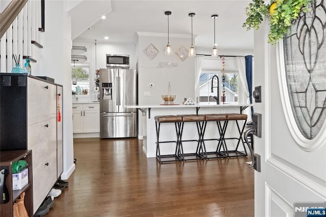 interior space featuring plenty of natural light, dark wood-style flooring, appliances with stainless steel finishes, and a breakfast bar area
