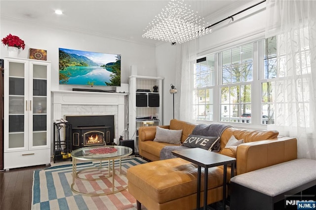 living room featuring crown molding, wood-type flooring, and a lit fireplace