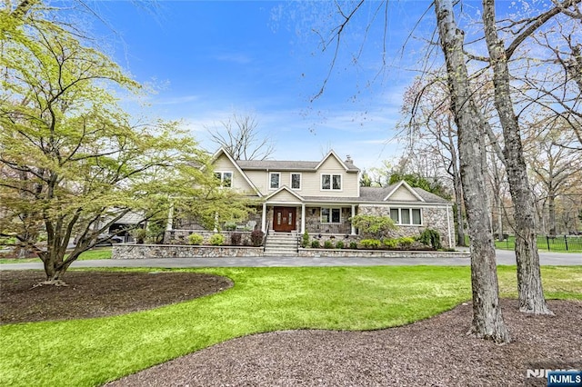 view of front of home featuring a front lawn, stone siding, and covered porch