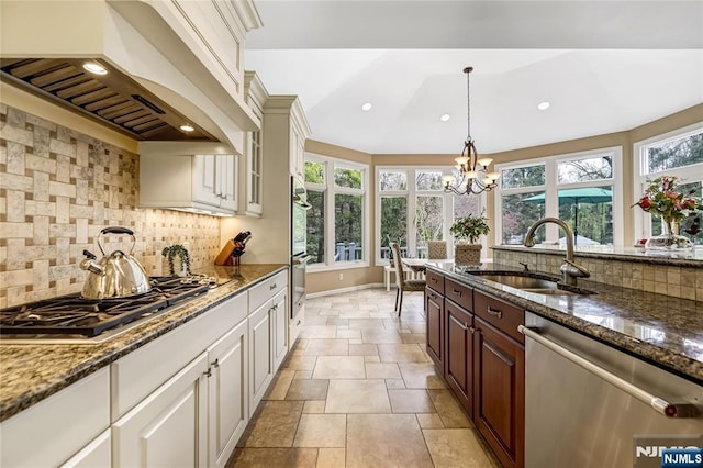 kitchen with decorative backsplash, a sink, appliances with stainless steel finishes, and premium range hood