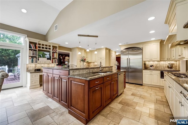 kitchen featuring decorative backsplash, a kitchen island with sink, a sink, and appliances with stainless steel finishes