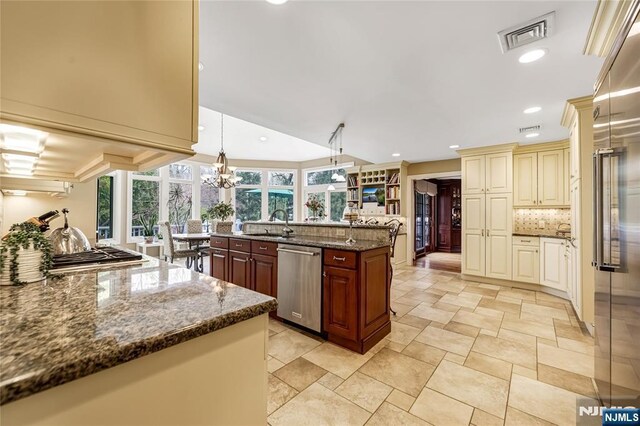 kitchen featuring cream cabinetry, stainless steel appliances, visible vents, a wealth of natural light, and tasteful backsplash