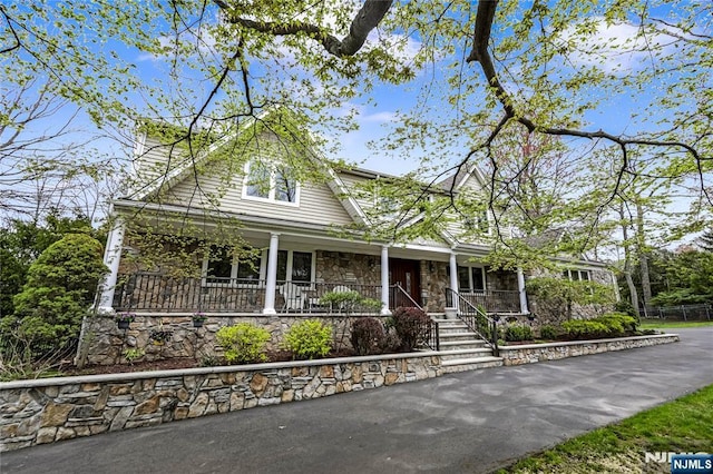 farmhouse-style home with stone siding and covered porch