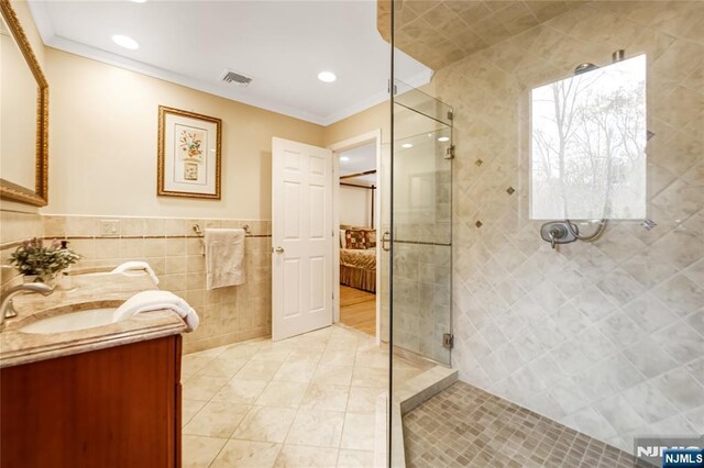 bathroom with visible vents, tile walls, crown molding, tiled shower, and ensuite bathroom