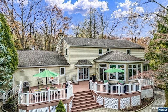 back of property with outdoor dining space, a shingled roof, a chimney, and a deck