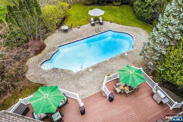 outdoor pool with a yard, a patio area, outdoor dining area, and a deck