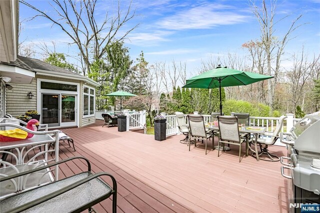 wooden terrace with outdoor dining area and area for grilling