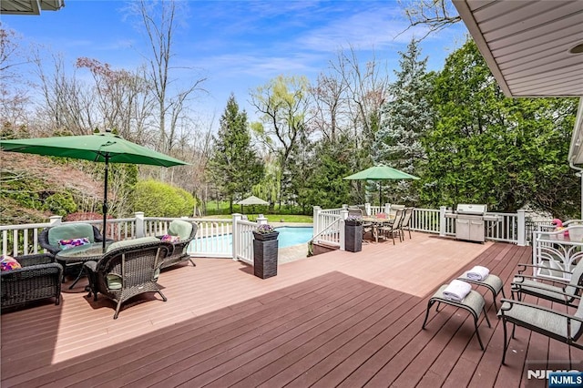 wooden terrace featuring grilling area, an outdoor hangout area, outdoor dining space, and an outdoor pool