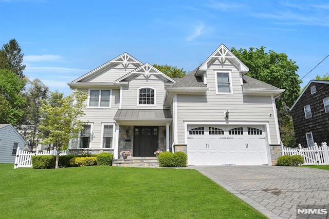 view of front of house with a standing seam roof, a front yard, fence, decorative driveway, and stone siding