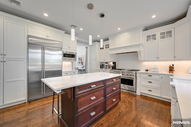 kitchen with built in appliances, white cabinetry, and visible vents