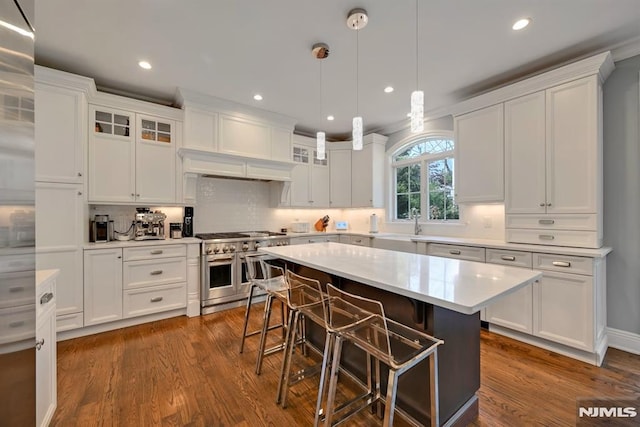 kitchen with double oven range, white cabinetry, light countertops, and a breakfast bar area