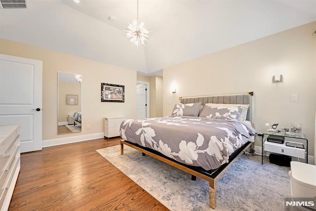 bedroom with baseboards, lofted ceiling, visible vents, and wood finished floors