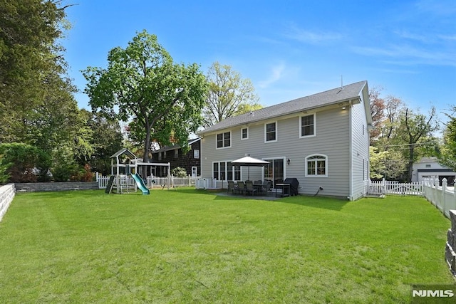 rear view of property with a playground, a yard, a patio area, and a fenced backyard