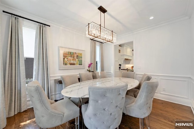 dining room with a wainscoted wall, an inviting chandelier, crown molding, and dark wood-style floors