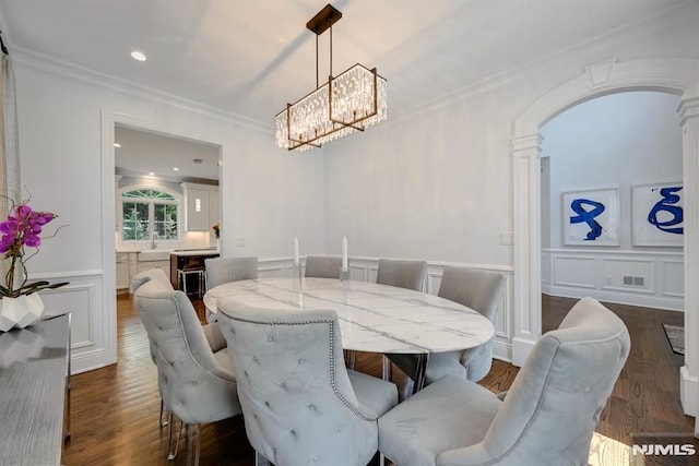 dining area with a notable chandelier, ornamental molding, a decorative wall, arched walkways, and dark wood-style floors