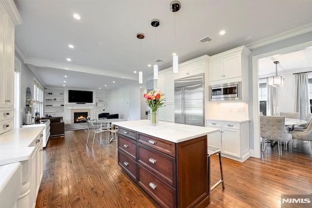 kitchen featuring crown molding, white cabinetry, dark wood-style flooring, and built in appliances