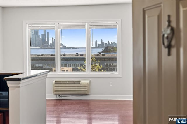 room details featuring baseboards, a wall unit AC, a city view, and wood finished floors