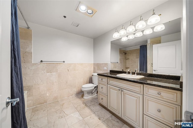 bathroom featuring vanity, toilet, tile walls, visible vents, and tiled shower
