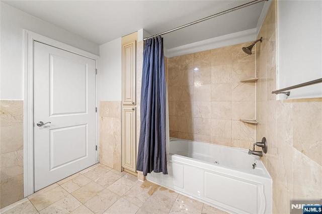 bathroom featuring tile walls, a wainscoted wall, and shower / tub combo with curtain