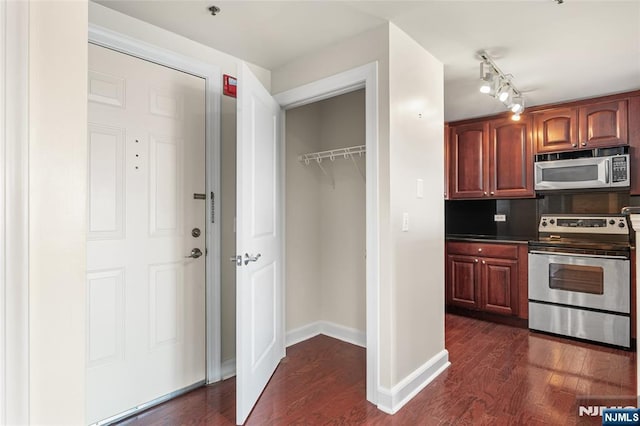 kitchen featuring decorative backsplash, dark countertops, appliances with stainless steel finishes, dark wood finished floors, and baseboards