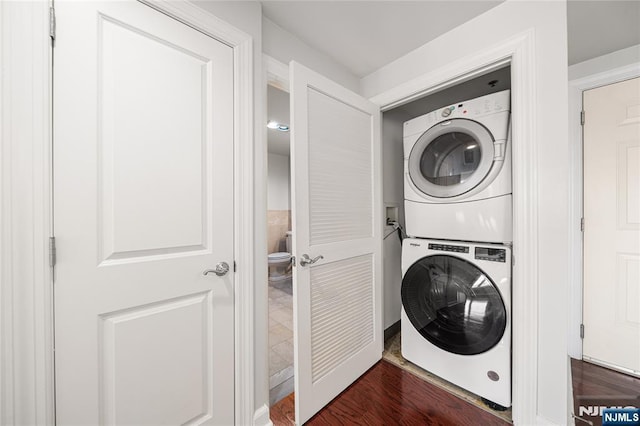 clothes washing area featuring stacked washer and dryer, laundry area, and dark wood finished floors