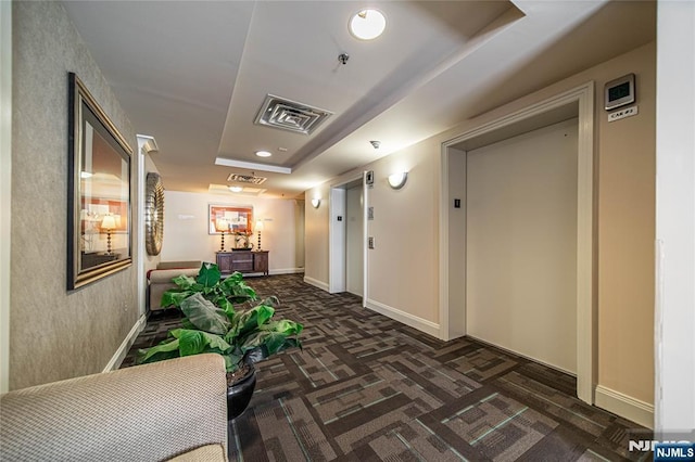 hall with elevator, visible vents, and dark colored carpet
