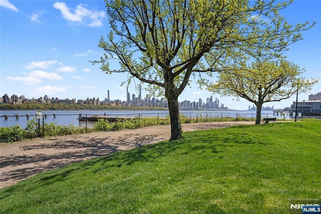 view of yard featuring a view of city, a water view, and fence