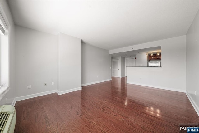 unfurnished living room with baseboards and dark wood-style floors