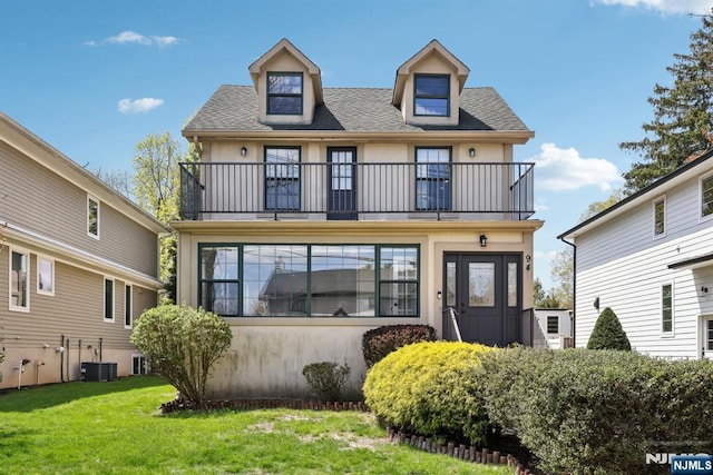 view of front of home with roof with shingles, stucco siding, a front yard, and a balcony