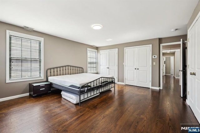 bedroom featuring baseboards, multiple closets, and wood finished floors