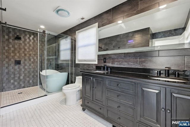 bathroom with visible vents, a sink, a shower stall, and tile walls