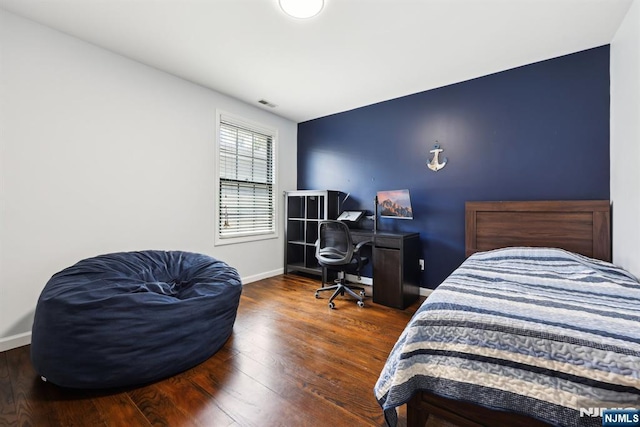 bedroom with baseboards, wood finished floors, and visible vents