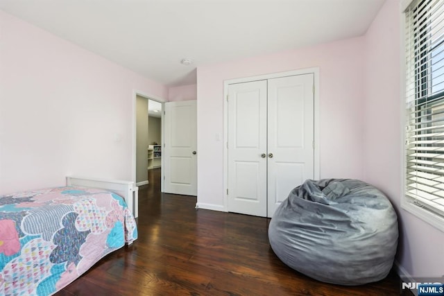 bedroom featuring baseboards, wood finished floors, and a closet