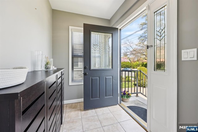 doorway to outside with baseboards, a healthy amount of sunlight, and light tile patterned floors