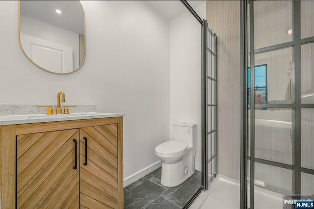bathroom featuring baseboards, toilet, vanity, and a stall shower
